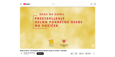 YouTube posnetek prikazuje negovalca, ki varno premika delno pokretno osebo iz postelje na invalidski voziček v domačem okolju.